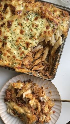 a casserole dish with meat and cheese on it next to a white plate