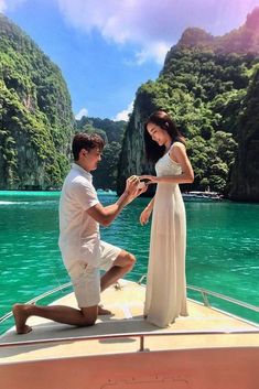 a man kneeling down on the back of a boat next to a woman in a white dress