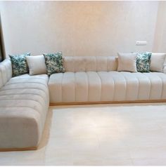 a large white couch sitting in a living room next to a wall with pillows on it