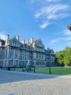 a large stone building sitting on top of a lush green field under a blue sky