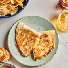 two quesadillas on a plate with chips and beer