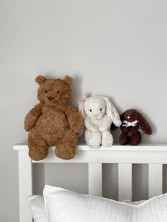 two stuffed animals sitting on top of a white shelf next to a pillow in a child's room