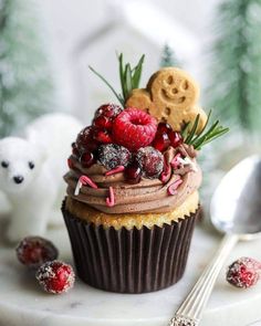 a cupcake decorated with raspberries, chocolate frosting and cookies on top