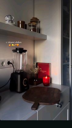 a blender sitting on top of a counter next to a cutting board and candle