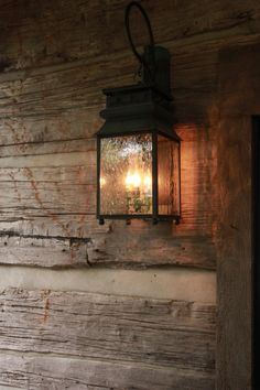 an old fashioned lantern hanging from the side of a wooden wall next to a door