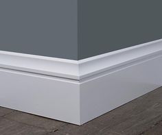 the corner of an empty room with gray walls and wood flooring on one side