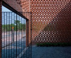 an entrance to a building made out of bricks and metal bars, with a street sign in the background