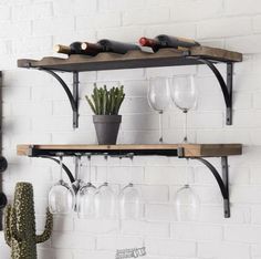 two wooden shelves with wine glasses and a cactus in a pot on the wall next to them