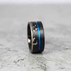 a wedding ring with blue and black inlays is on top of a marble surface