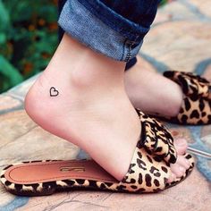 a woman's foot with a heart tattoo on her left ankle and leopard print slippers