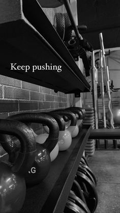 kettles are lined up on a shelf in a gym room with the words keep pushing above them