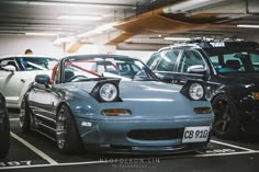 several cars parked in a parking garage with their hoods open and the lights on