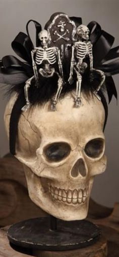 a skull with two skeletons sitting on top of it's head, wearing black hair