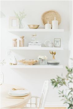 white shelves with plates, bowls and vases on them in a dining room setting