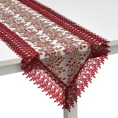 the table is covered with red lace and has an intricate design on it's edge