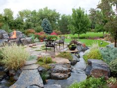 an outdoor patio area with rocks, plants and fire pit in the background on a cloudy day