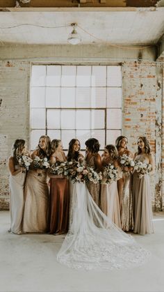 a group of women standing next to each other in front of a brick wall holding bouquets