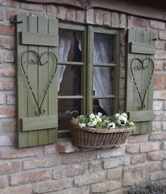 two windows with green shutters and white flowers in a basket on the window sill