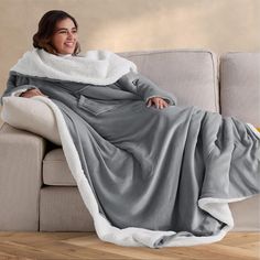 a woman sitting on a couch wrapped in a blanket