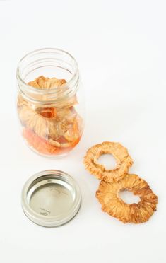 a jar filled with dried fruit sitting next to a metal container full of sliced fruit