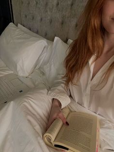 a woman laying in bed reading a book