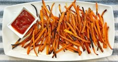 a white plate topped with french fries next to ketchup on a blue and white table cloth