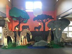 an elephant, giraffes and other animals are on display in the lobby