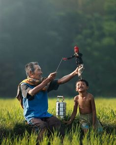 an old man and young boy sitting in the grass with a toy on his shoulder