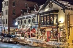 a city street with cars parked on the side of it and christmas decorations all around