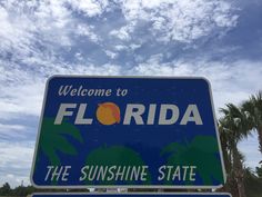 a welcome to florida sign with palm trees and blue sky in the backround