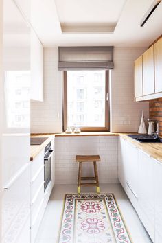 a kitchen with white cabinets and an area rug