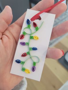 a hand holding a piece of paper with colorful beads on it