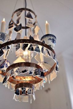 a chandelier hanging from the ceiling with blue and white dishes on it's sides