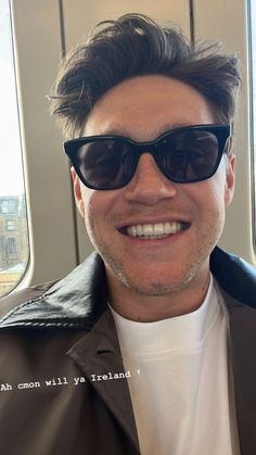 a man wearing sunglasses is smiling for the camera while riding on an airplane with his hair pulled back