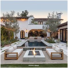 an outdoor living area with couches and fire pit in front of a large house