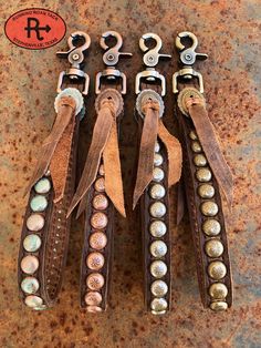 four pairs of leather and metal bracelets with buttons on them sitting next to each other