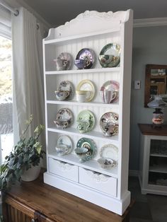 a white china cabinet with plates on it