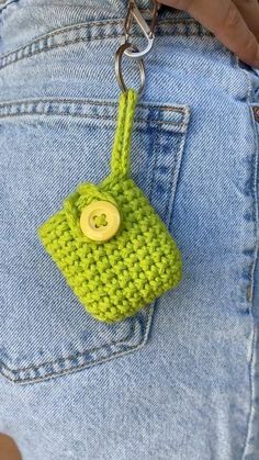 a crocheted bag with a button attached to it's back pocket is being held by someone