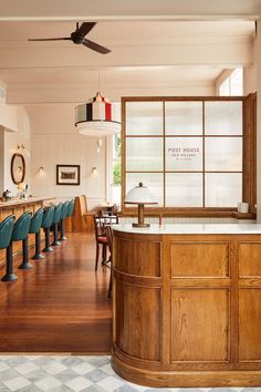 an empty restaurant with wooden tables and blue chairs in front of the bar area, looking into the dining room