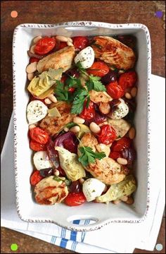 a white dish filled with lots of food on top of a wooden table