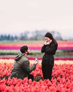 two people standing in a field of tulips talking on their cell phones and drinking coffee