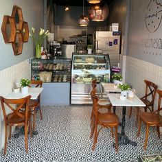 the inside of a restaurant with wooden chairs and tables in front of an open counter