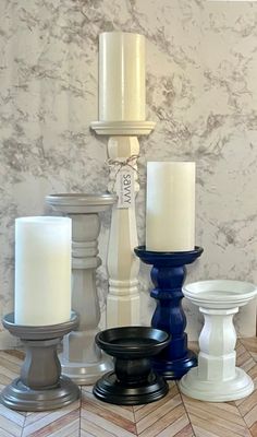 there are many different types of candles on the floor in front of a marble wall