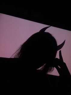 the silhouette of a person holding scissors in front of a screen with a devil's head on it