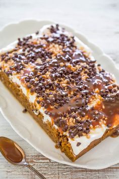 a piece of cake on a white plate with chocolate chips and caramel drizzle