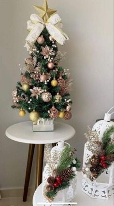 a small christmas tree sitting on top of a white table next to a vase filled with flowers