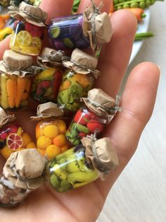 a hand holding several small jars filled with different types of fruits and veggies