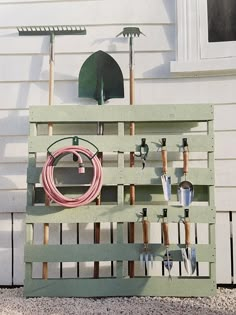 a wooden pallet with gardening tools hanging on it