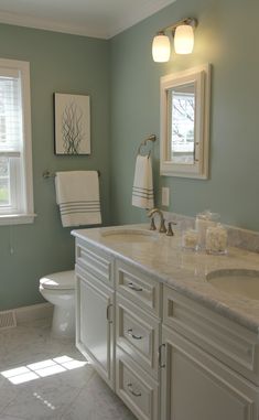 a bathroom with white cabinets and marble counter tops