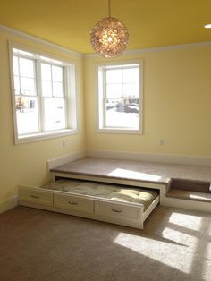 the sun shines through two windows in an empty room with a bed and drawers